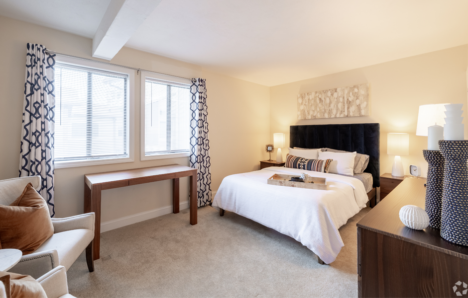 Bedroom with bed, windows, lamps, and chairs